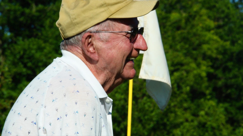 An older gentleman smiles after making us putt during a golf club outing