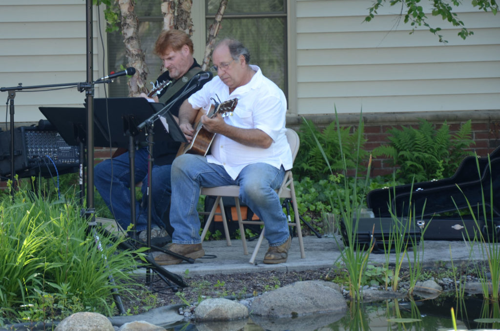 Two guitarists play live music for the residents around the patio area and koi pond